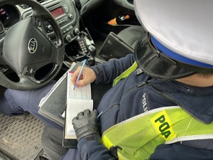zdjęcie przedstawia policjanta drogówki w radiowozie wypisującego mandat