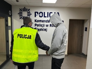 zdjęcie przedstawia pomieszczenia komendy, policjant z zatrzymanym