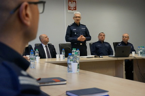 zdjęcie przedstawia siedzących przy stole zaproszonych gości i komendantów, jeden z nich stoi i przemawia