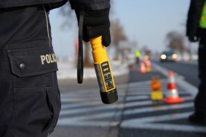 zdjęcie poglądowe - policjant na ulicy, w ręku trzyma alkotest do badania trzeźwości