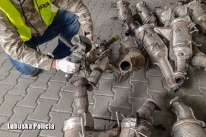 zdjęcie poglądowe, policjant przy leżących katalizatorach