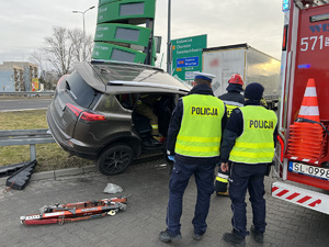 zdjęcie z miejsca wypadku rozbity samochód, straż pożarną i stojących obok dwóch policjantów