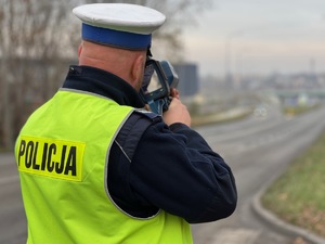 zdjęcie przedstawia, policjanta z drogówki z radarowym miernikiem prędkości podczas pracy