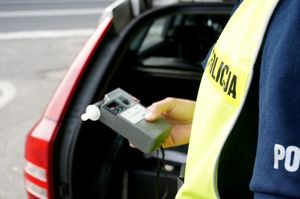 zdjęcie przedstawia policjanta przy radiowozie z alkotesterem w ręku