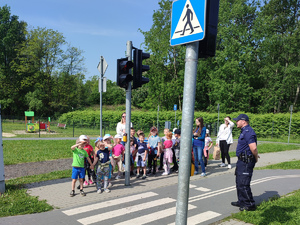 zdjęcie - dzieci z przedszkola z dzielnicowym przy symulowanym przejściu dla pieszych miasteczka ruchu drogowego