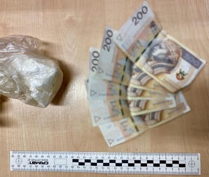 zdjęcie - zabezpieczony woreczek z narkotykami i pieniądze przejęte na poczet przyszłych kar, poniżej skalówka kryminalistyczna