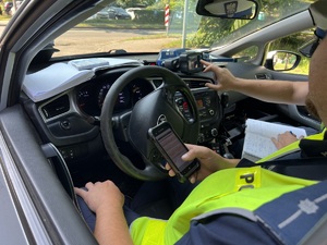zdjęcie wnętrza radiowozu z policjantami kontrolującymi dokumenty kierowcy, który przekroczył prędkość