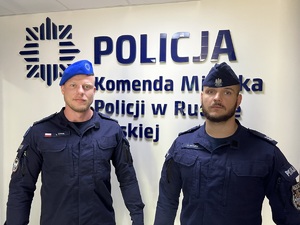zdjęcie - dwaj policjanci na tle ściany z napisem policja, jeden z błękitnym beretem