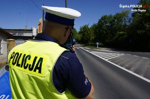zdjęcie - policjant z drogówki w trakcie pomiaru prędkości radarowym miernikiem ręcznym