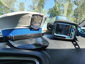 wnętrze radiowozu, policyjna czapka i miernik prędkości