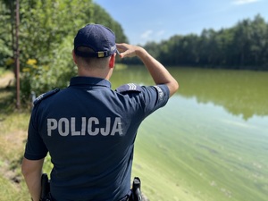 zdjęcie policjanta stojącego na brzegu stawu