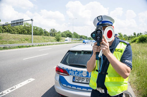 zdjęcie przedstawiające policjanta z drogówki przy radiowozie na drodze szybkiego ruchu