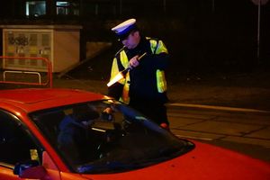 zdjęcie archiwalne - policjant kontroluje trzeźwość kierowcy czerwonego samochodu