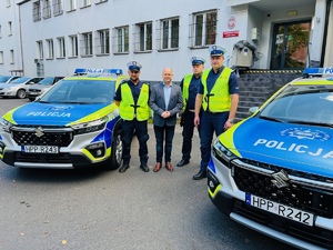 zdjęcie przedstawia trzech policjantów i prezydenta stojących przy nowych radiowozach przed budynkiem komendy