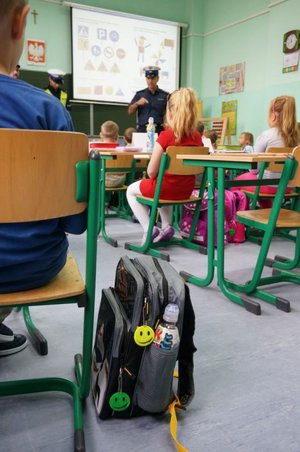 zdjęcie archiwalne - policjanci w trakcie wizyty w klasie, dzieci przy ławkach, tornistry z odblaskami