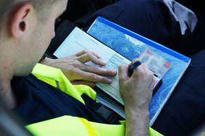 zdjęcie policjanta wypisującego bloczek mandatu karnego