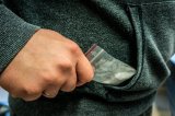 zdjęcie przedstawiające rękę z woreczkiem białego proszku sięgającą do kieszeni