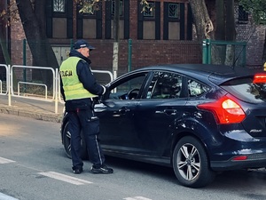 zdjęcie policjantaz drogówki w trakcie kontroli trzeźwości kierowcy samochodu osobowego przejeżdżającego w rejonie szkoły