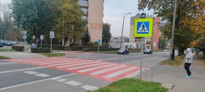 zdjęcie ulicy w centrum miasta z przejściem dla pieszych wymalowanym biało czerwonymi pasami