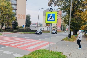 zdjęcie  ulicy w centrum miasta z przejściem dla pieszych i młodego mężczyznę idącego w jego kierunku