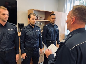 zdjęcie z gabinetu komendanta, trzech policjantów i komendant przed nimi składający gratulacje