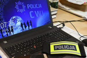 zdjęcie poglądowe - komputer przenośny, opaska z napisem policja