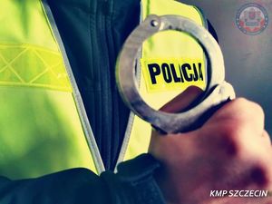 zdjęcie poglądowe, policjant w kamizelce odblaskowej trzymający w ręku kajdanki