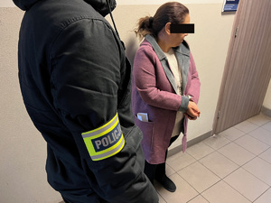 zdjęcie przedstawia policjanta stojącego na korytarzu komendy z zatrzymaną kobietą