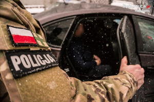 zdjęcie poglądowe - policjant przy samochodzie służbowym