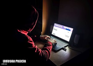 zdjęcie poglądowe - osoba w ciemnym pokoju korzysta z komputera przenośnego