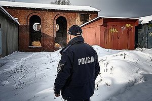 zdjęcie poglądowe - policjant stojący w zimie przed opuszczonym budynkiem