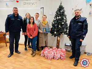 zdjęcie - policjanci i pracownicy świetlicy pozują do pamiątkowego zdjęcia przy choince w świetlicy