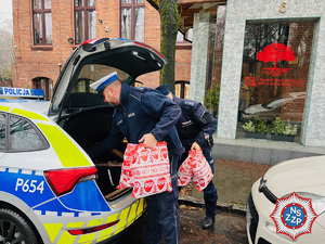 zdjęcie - policjanci wyciągają świąteczne torby z bagażnika radiowozu