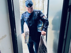 zdjęcie przedstawia policjanta niosącego prezenty