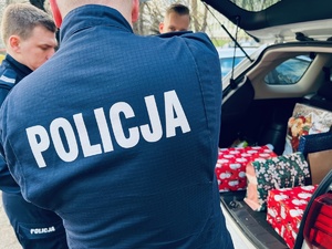 zdjęcie przedstawia policjantów stojących przy samochodzie z prezentami