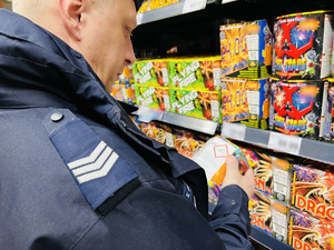 zdjęcie z kontroli miejsc sprzedaży fajerwerków - policjant sprawdza czy instrukcja obsługi jest czytelna dla przyszłego użytkownika