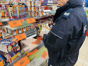 zdjęcie z kontroli miejsc sprzedaży fajerwerków - policjant stoi przed koszami z petardami i kontroluje czy pudełka mają odpowiednie oznaczenia