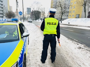 zdjęcie przedstawia policjanta przy radiowozie w trakcie reakcji na wykroczenia kierowców