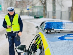 zdjęcie przedstawia policjanta przy radiowozie