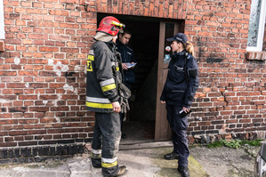zdjęcie poglądowe - strażak i policjantka stojący przy wejściu do budynku - zdjęcie z archiwum rudzkiej policji