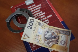zdjęcie poglądowe - książka kodek karny, kajdanki, banknot 200 złotych