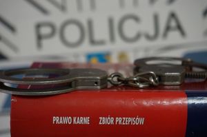 zdjęcie poglądowe przedstawiające logo policji, kajdanki i książka ze zbiorem przepisów prawa