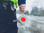 zdjęcie archiwalne - policjant z drogówki na drodze z tarczą do zatrzymywania pojazdów