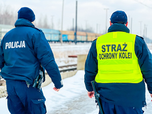 zdjęcie przedstawia policjanta i sokistę idących peronem