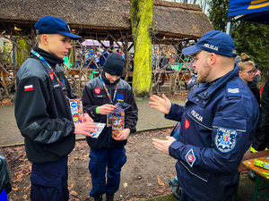 zdjęcie przedstawia policjanta rozmawiającego z kwestującymi uczniami mundurówki