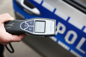 zdjęcie poglądowe - policyjny alkotest w tle drzwi radiowozu