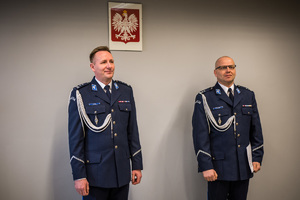 sala narad, komendant i jego zastępca stoją przy ścianie z wiszącym godłem