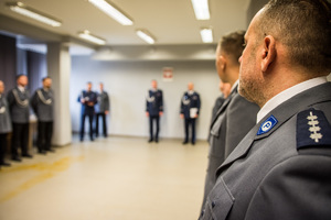 sala narad po prawej stoją policjanci, na wprost widoczne sylwetki komendanta, zastępcy i innych policjantów