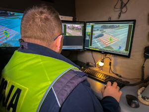 zdjęcie przedstawia policjanta drogówki siedzącego w samochodzie monitoringu i obserwującego na ekranie monitora przejście dla pieszych