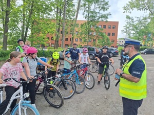 zdjęcie przedstawia rowerzystów i policjanta zadającego pytania dzieciom